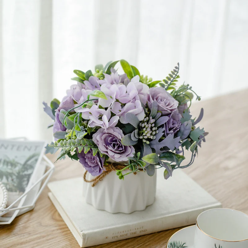 Seidenblumenarrangement in einem mit Schnur umwickelten Keramikpflanzer als Tischmittelpunkt