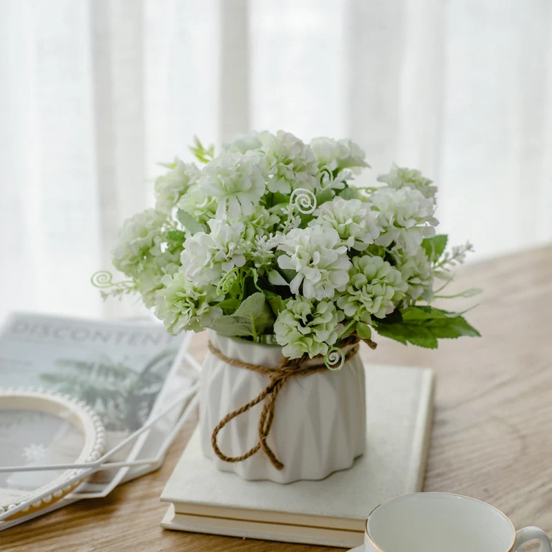 Seidenblumenarrangement in einem mit Schnur umwickelten Keramikpflanzer als Tischmittelpunkt