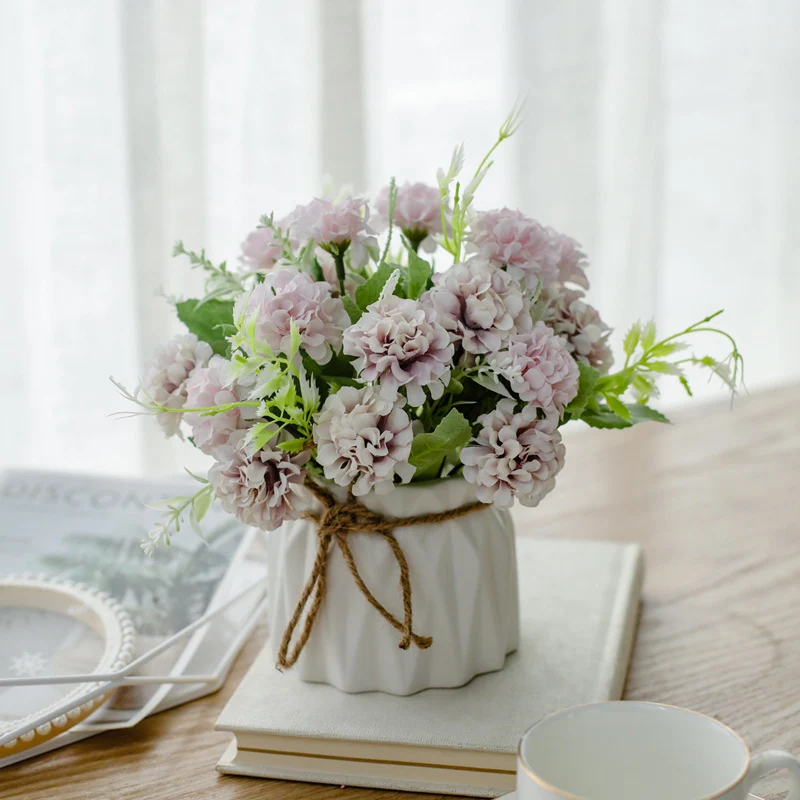 Seidenblumenarrangement in einem mit Schnur umwickelten Keramikpflanzer als Tischmittelpunkt