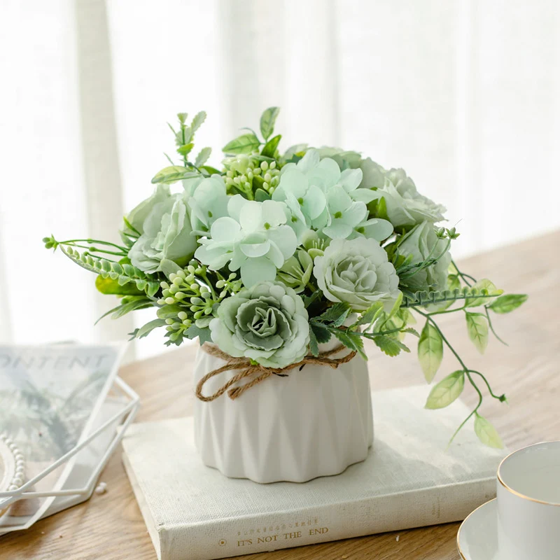 Seidenblumenarrangement in einem mit Schnur umwickelten Keramikpflanzer als Tischmittelpunkt