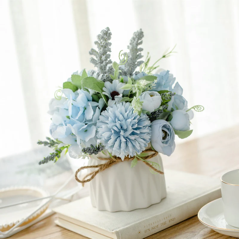 Seidenblumenarrangement in einem mit Schnur umwickelten Keramikpflanzer als Tischmittelpunkt