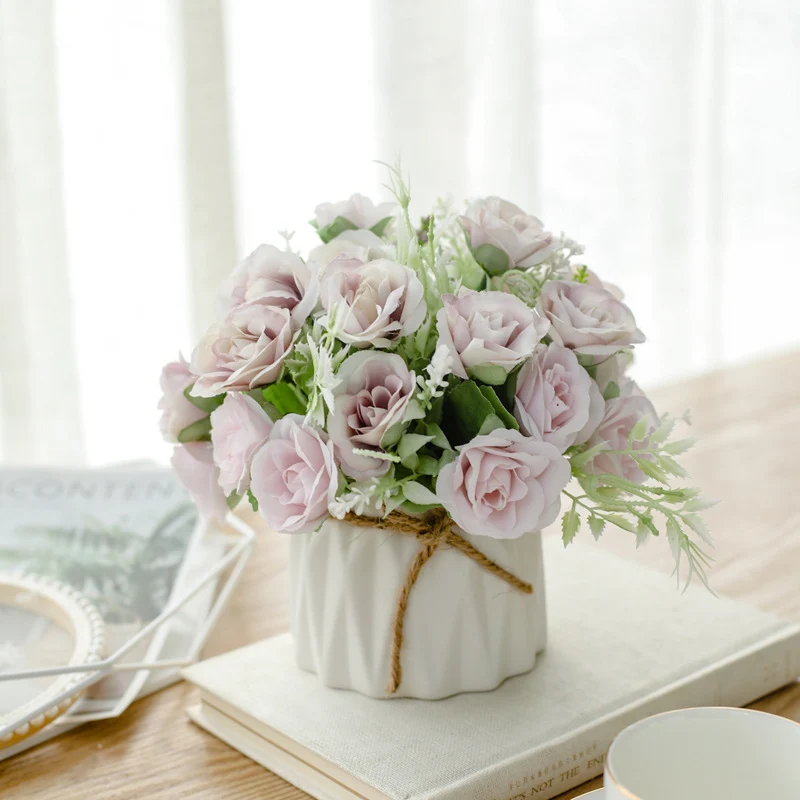 Seidenblumenarrangement in einem mit Schnur umwickelten Keramikpflanzer als Tischmittelpunkt
