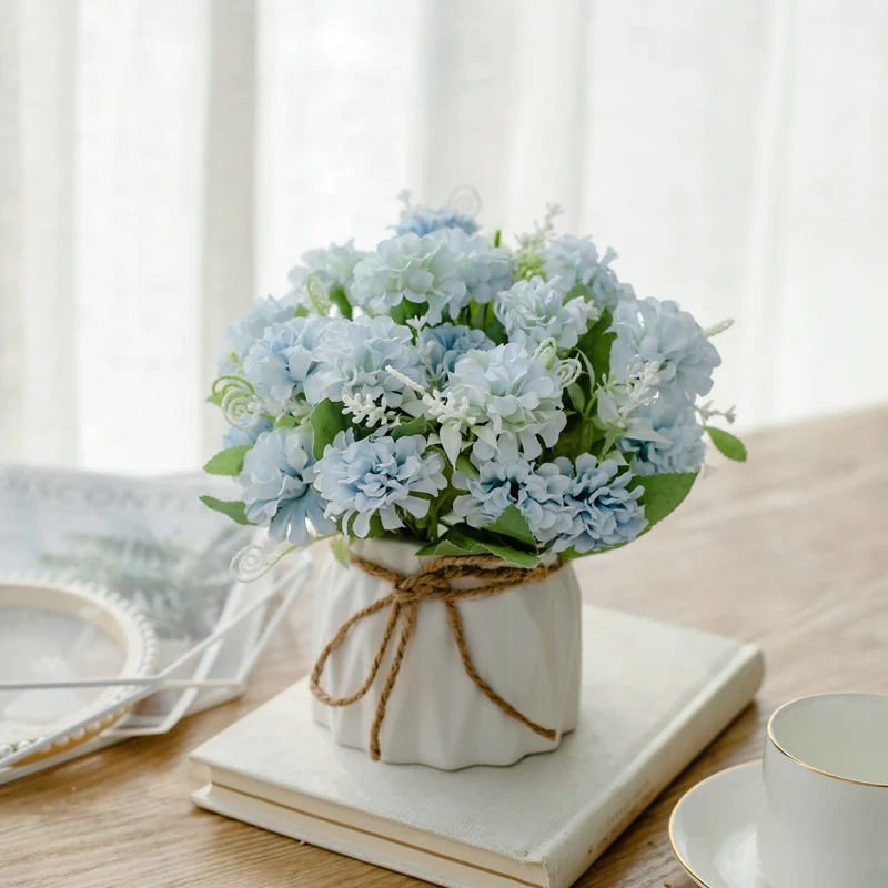 Seidenblumenarrangement in einem mit Schnur umwickelten Keramikpflanzer als Tischmittelpunkt