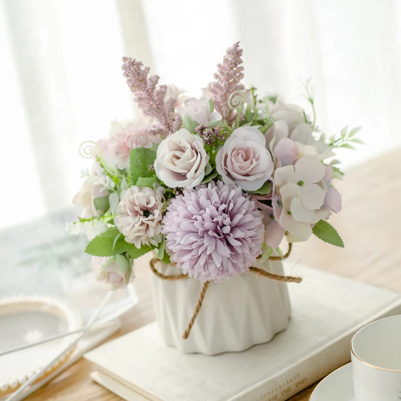 Seidenblumenarrangement in einem mit Schnur umwickelten Keramikpflanzer als Tischmittelpunkt