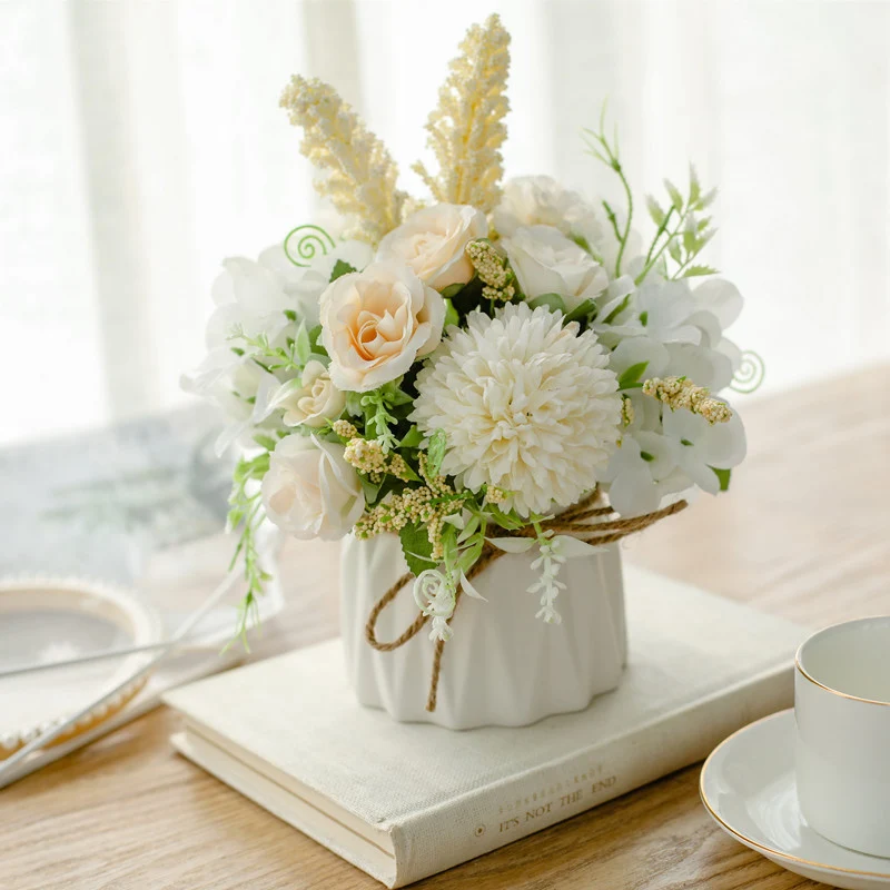 Seidenblumenarrangement in einem mit Schnur umwickelten Keramikpflanzer als Tischmittelpunkt