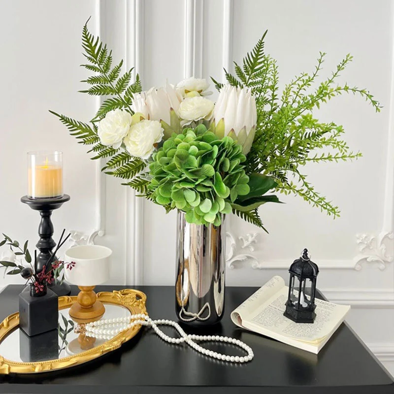 Spiegelnde hohe zylindrische dekorative Metallvase mit künstlicher Hortensie und Protea Arrangement