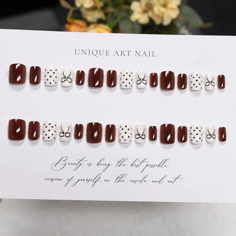 Dekorative Press-On Nageldesign mit Schleife und Punkten