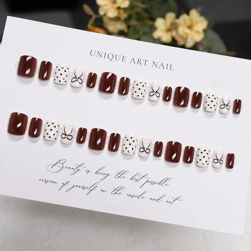 Dekorative Press-On Nageldesign mit Schleife und Punkten