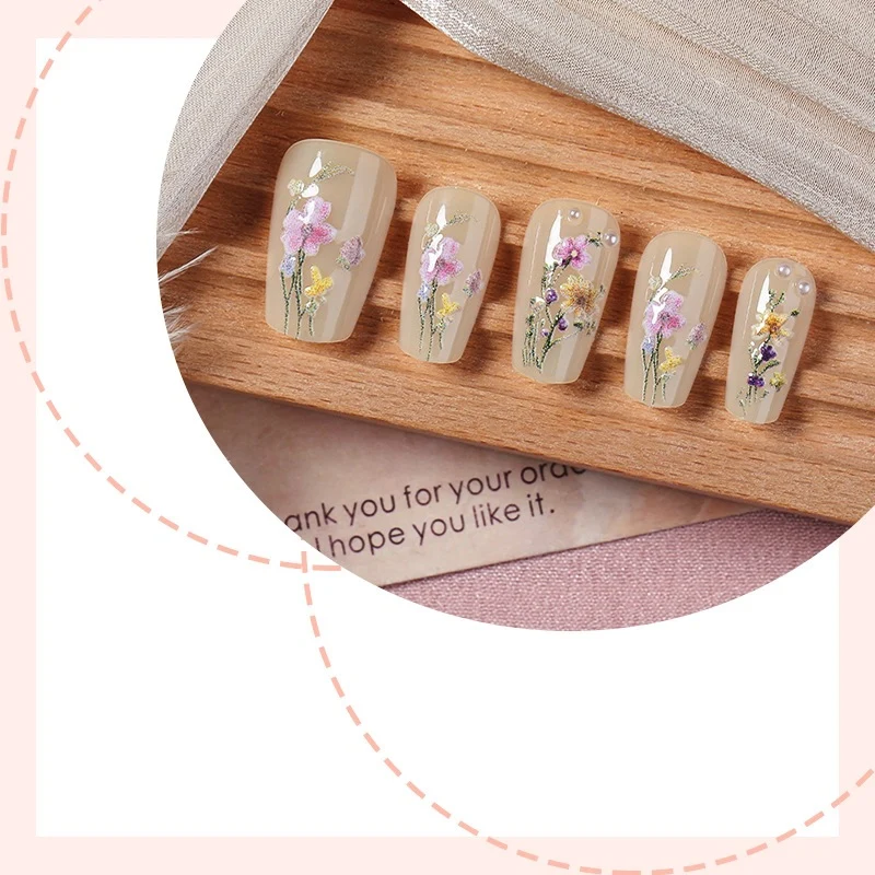 Kunstnagelset mit floralen Verzierungen und glamourösen Details Brehn