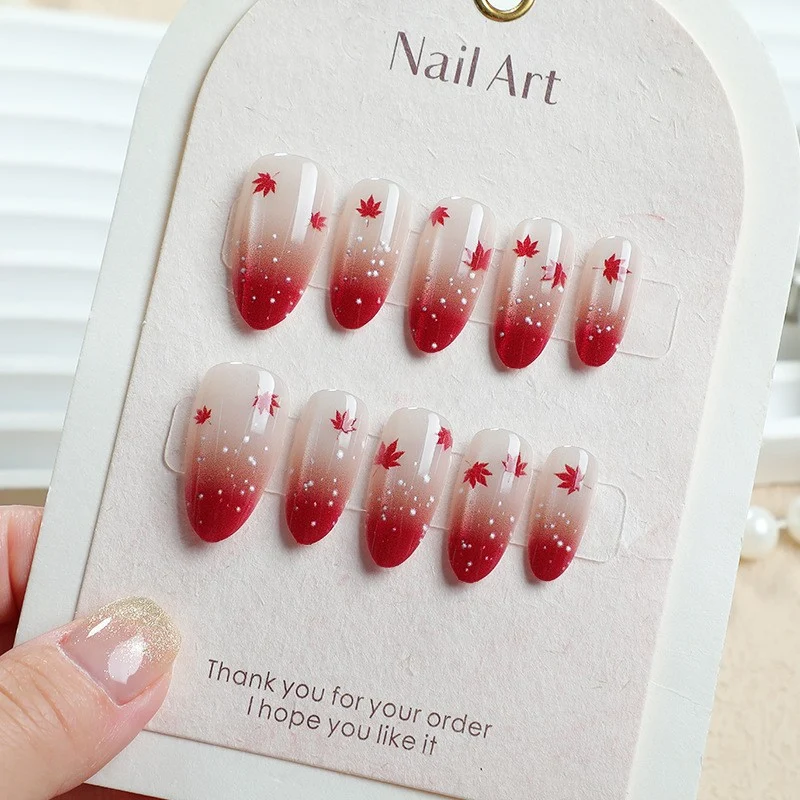 Kunstnagelset mit elegantem Rot-Ombré-Look und zarten Ahornblättern Brehn