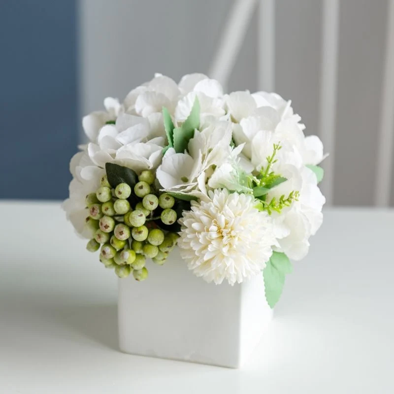 Lebensechte Blumenarrangement in dekorativem quadratischen Pflanzgefäß